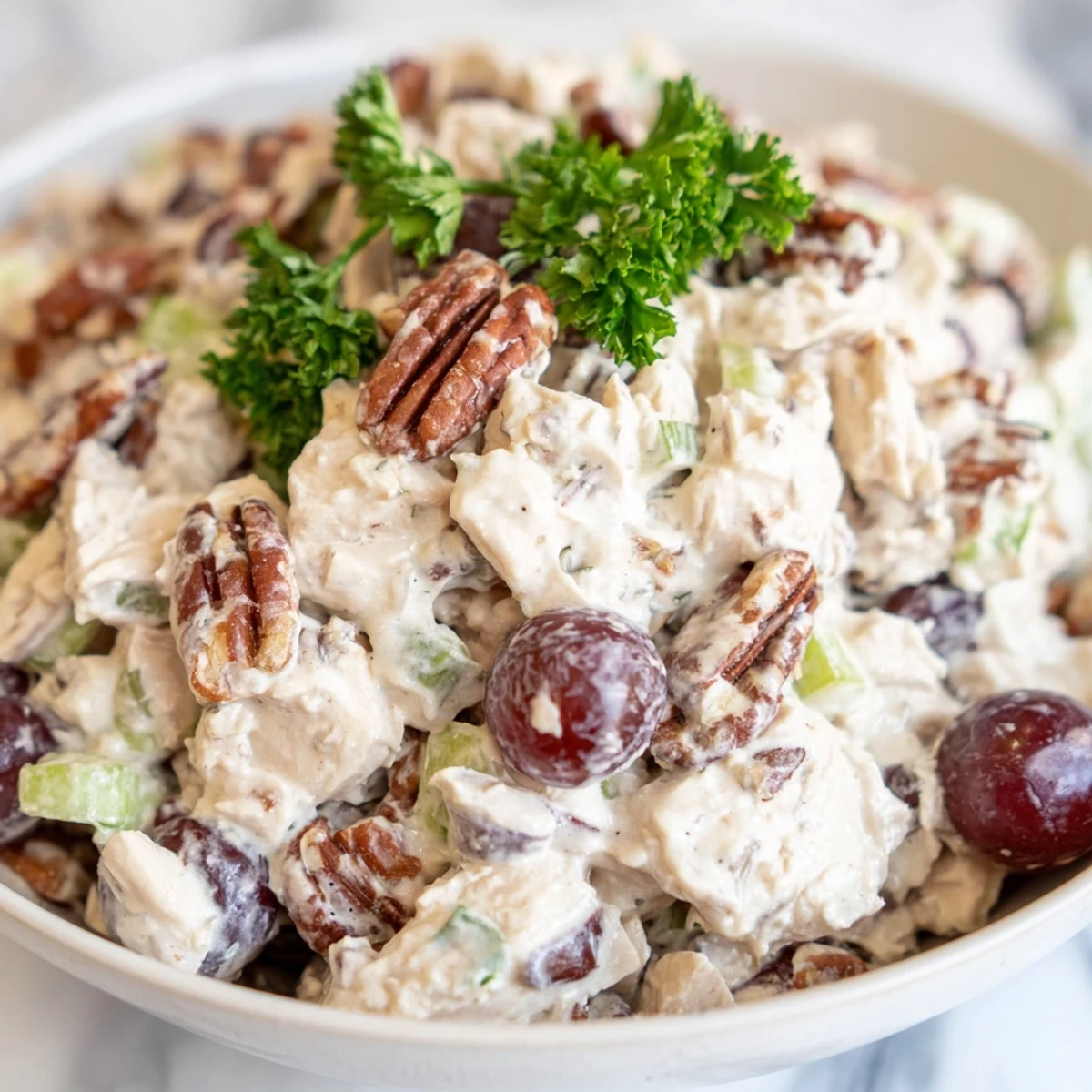 A close-up view of Chicken Pecan Salad showing diced celery, halved grapes, and toasted pecan halves.