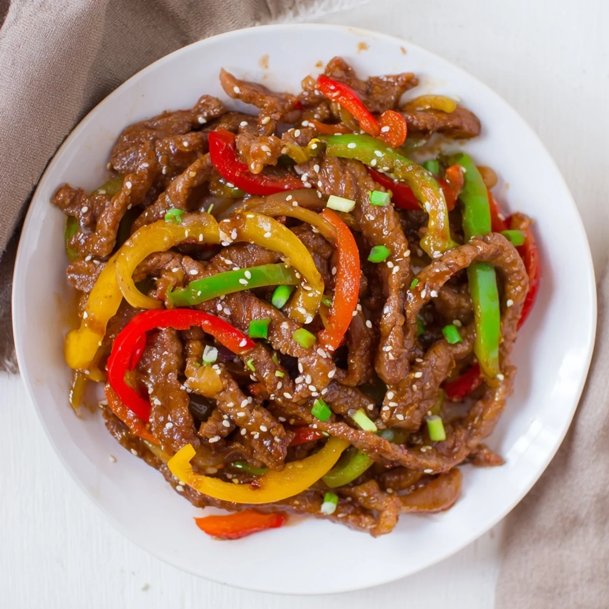 Savory Spicy Beef and Bell Pepper Stir Fry served over fluffy white rice with scallions and sesame seeds.