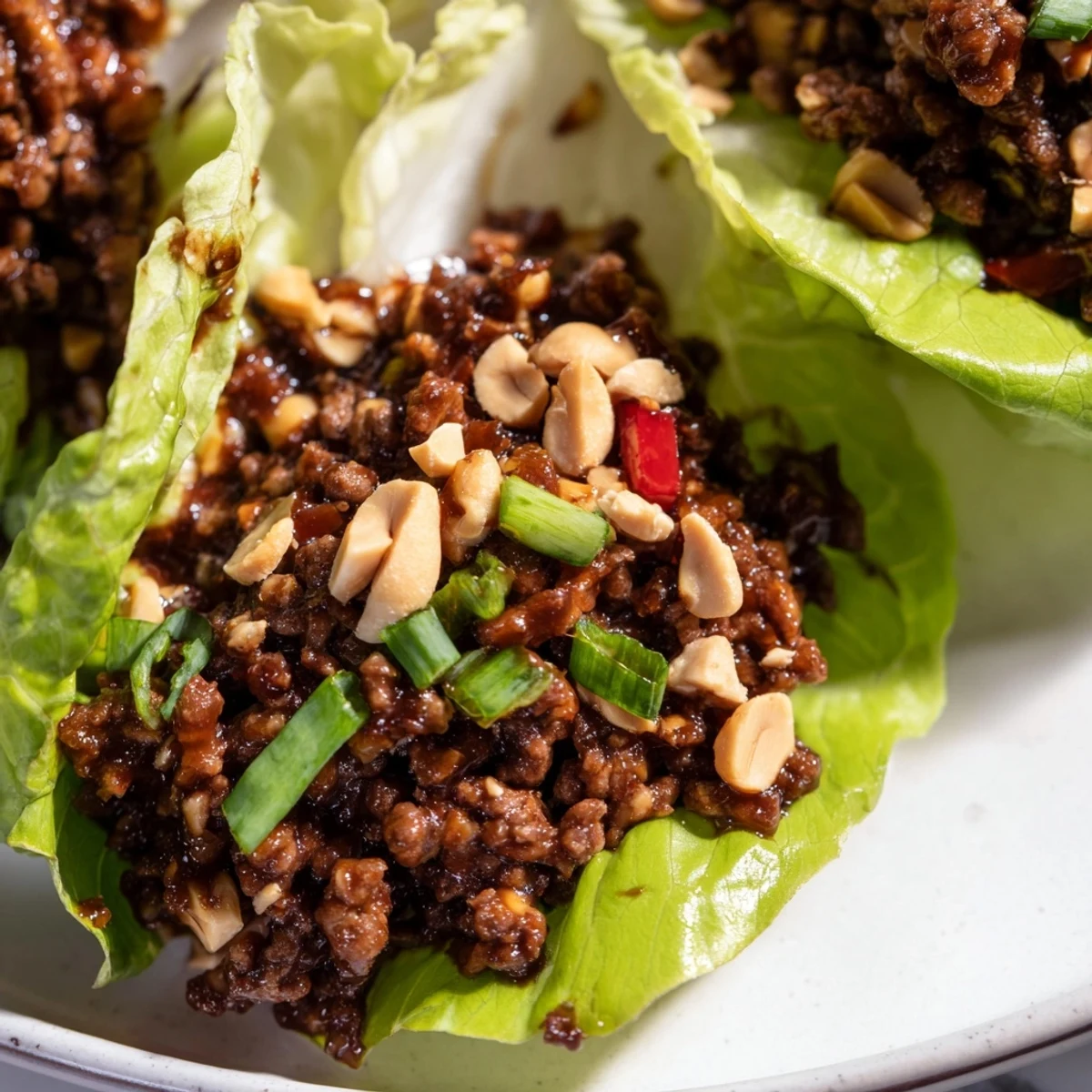 Freshly prepared Beef Lettuce Wraps with Hoisin Sauce are spooned into crisp, cool butter lettuce cups and topped with chopped peanuts.