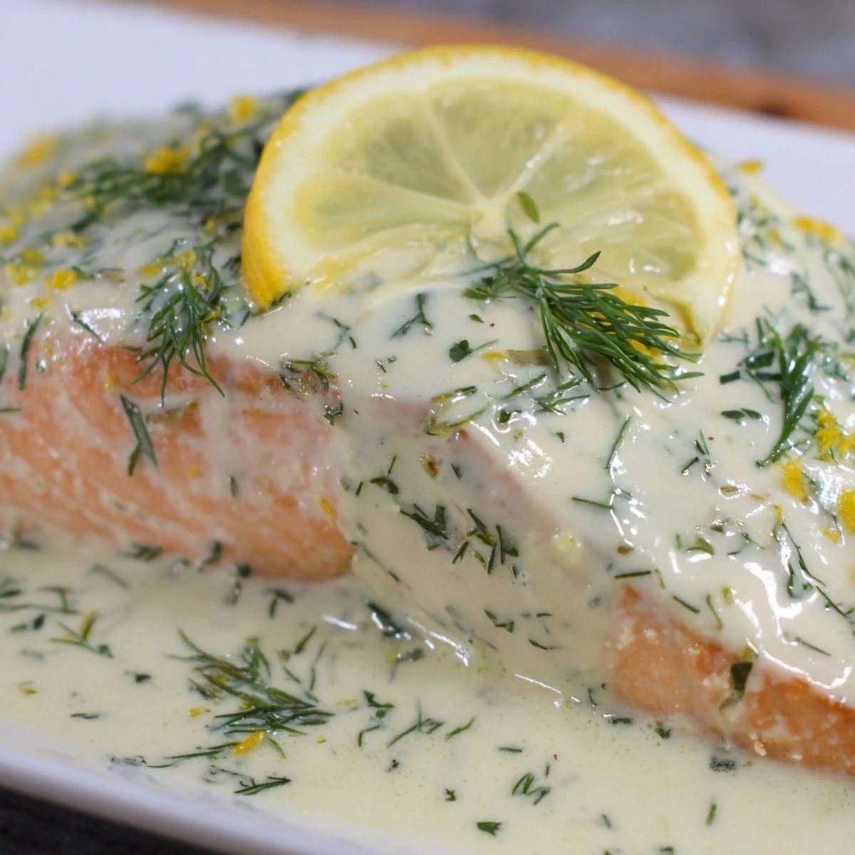 Golden-brown baked salmon fillets topped with creamy dill and lemon sauce served with roasted potatoes.