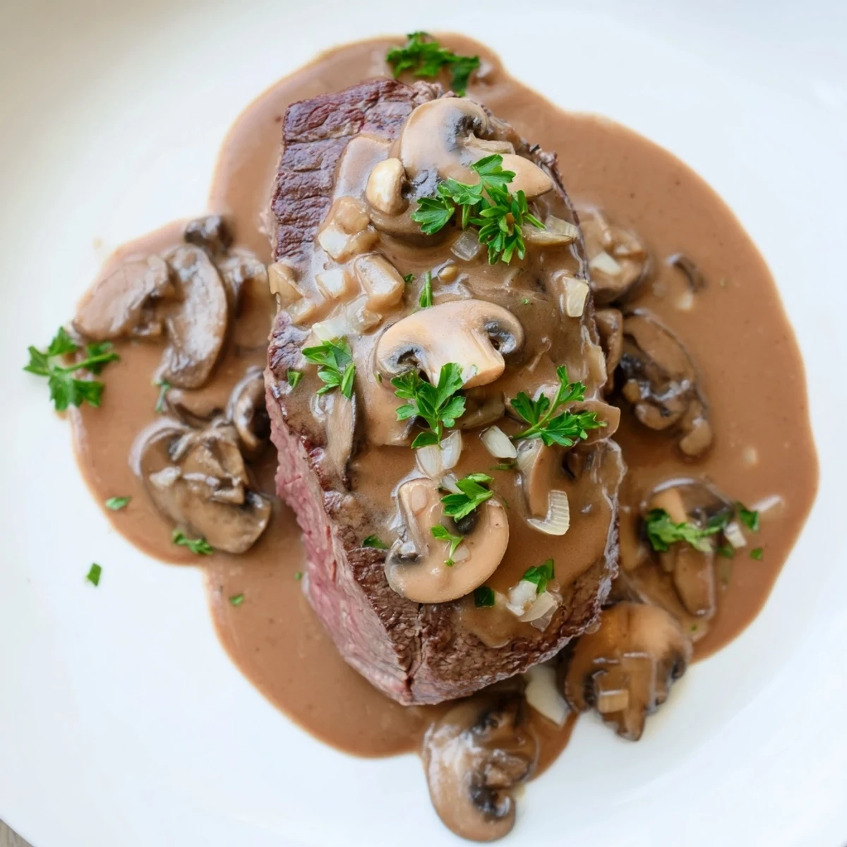 Two tender beef tenderloin steaks, smothered in mushroom Diane sauce and served alongside roasted potatoes and asparagus.
