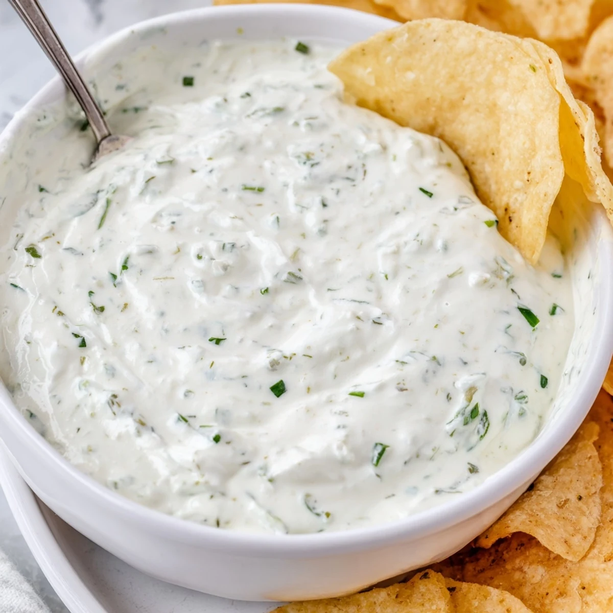 An inviting serving of Creamy Dip Bowl with Chips, with the tangy dip in a ceramic bowl and colorful tortilla chips arranged around it.