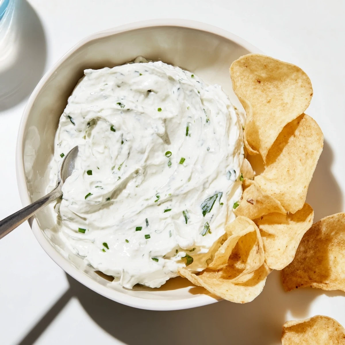 A bowl of Creamy Dip Bowl with Chips, the dip textured with herbs and served alongside crisp, kettle-cooked potato chips for dipping.