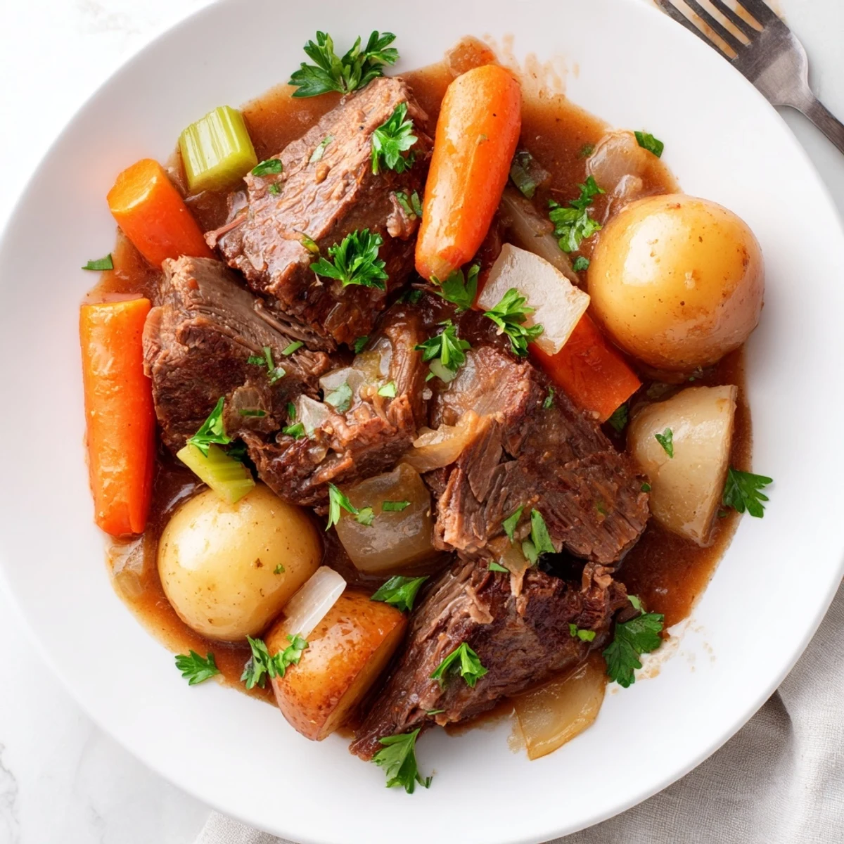 Sliced beef and roasted vegetables from the Slow Cooker Beef Roast Dinner are served in a shallow bowl with fresh parsley garnish.