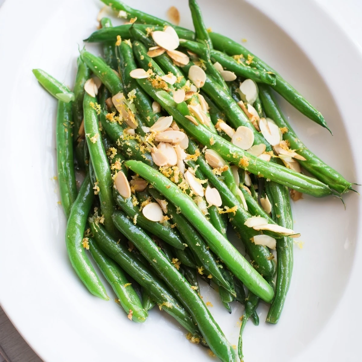 Crisp green beans with lemon and almonds glisten in a skillet, garnished with fresh zest for a bright, easy side.