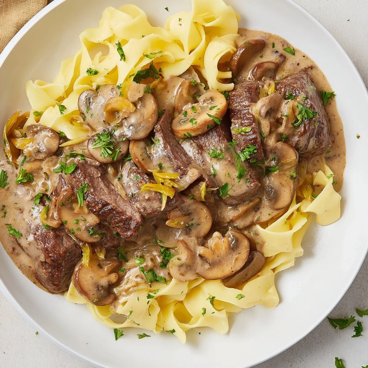 A close-up of beef stroganoff with egg noodles reveals a savory mushroom sauce and buttery noodles.
