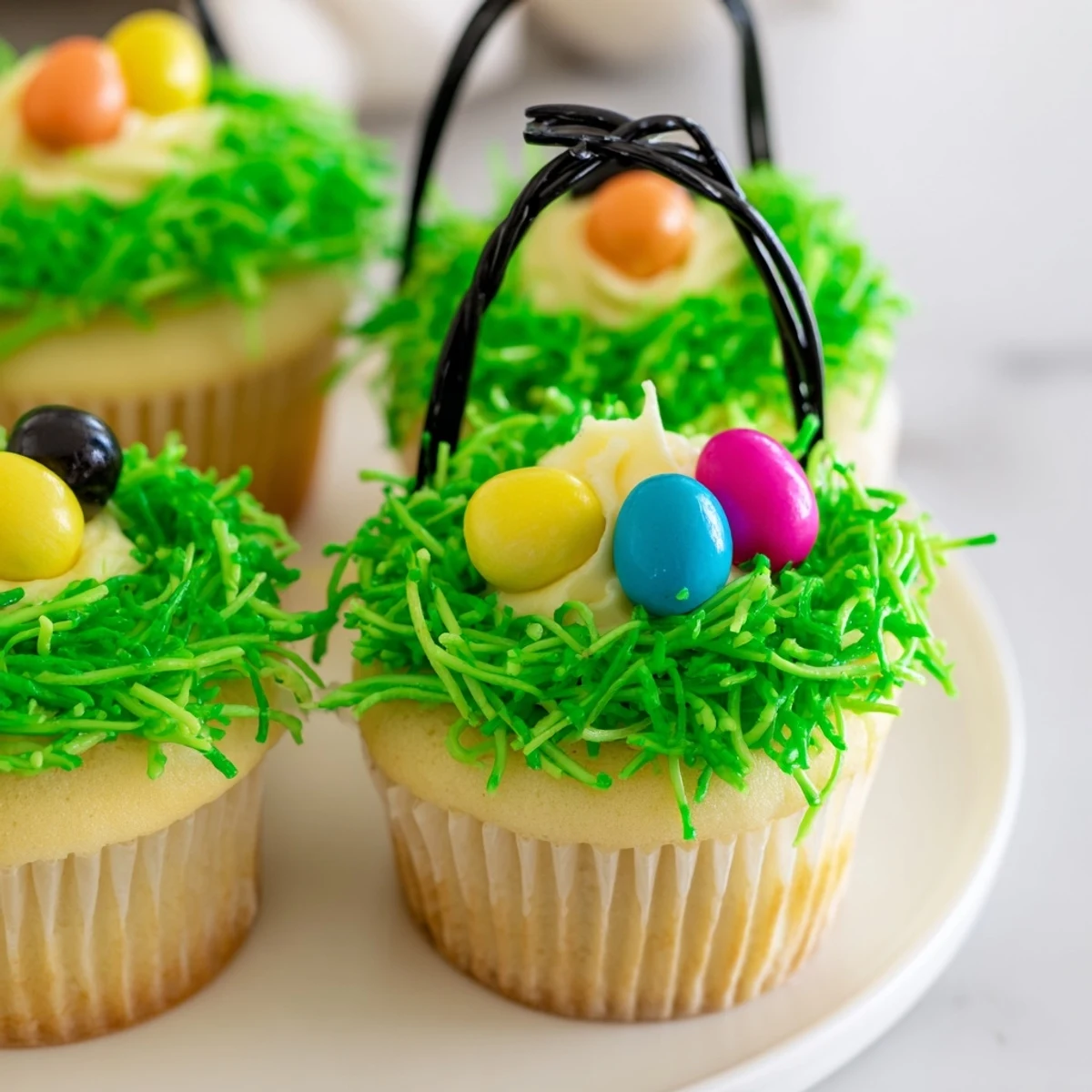 Easter Basket Cupcakes with coconut grass and jelly bean eggs on a white ceramic plate.