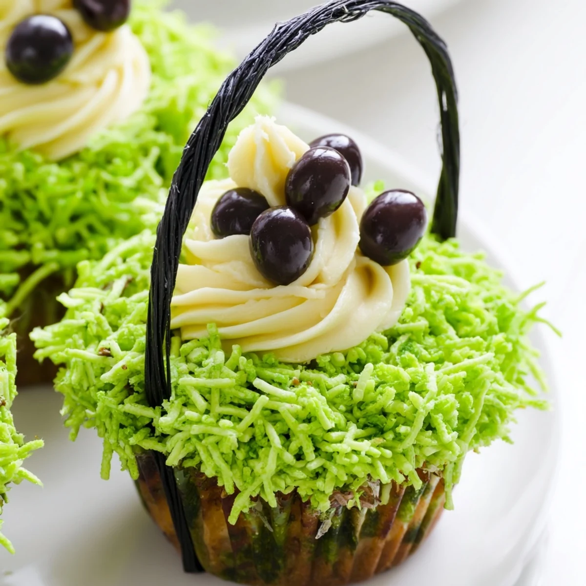 A close-up of Easter Basket Cupcakes decorated with licorice basket handles, pastel candies, and fluffy green shredded coconut.