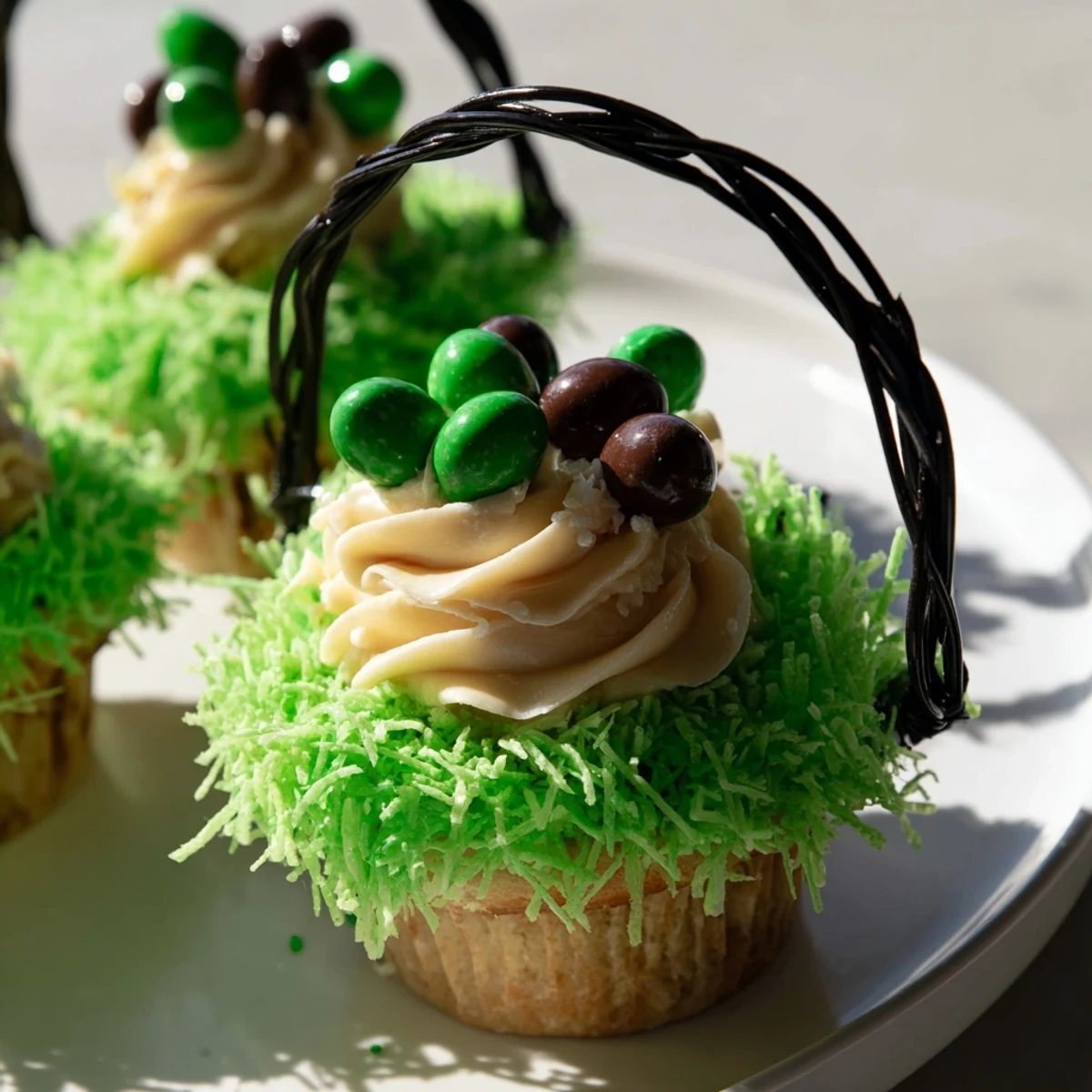 Easter Basket Cupcakes featuring sweet buttercream frosting, green coconut grass, and mini chocolate eggs for spring celebrations.