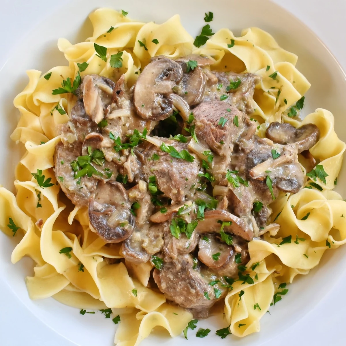Tender beef and mushrooms in a creamy sauce over egg noodles for Beef Stroganoff.