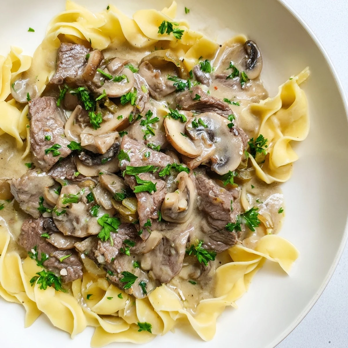 Savory Beef Stroganoff served over buttery egg noodles, garnished with fresh parsley for color.
