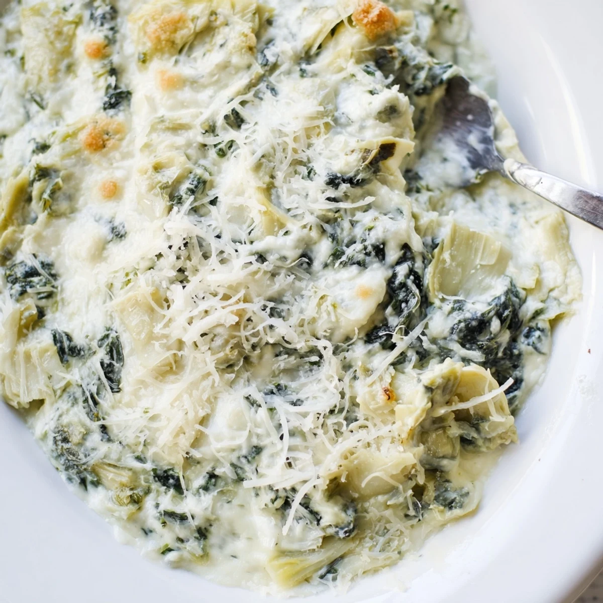 Freshly baked Creamy Spinach and Artichoke Dip with Chips in a ceramic bowl, surrounded by crispy tortilla chips on a wooden table.