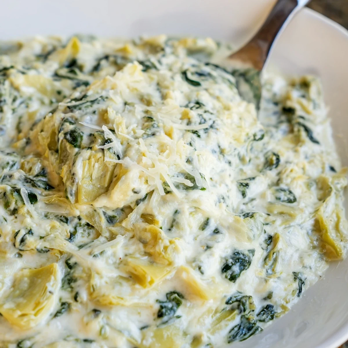 Rich and cheesy Creamy Spinach and Artichoke Dip with Chips, garnished with green spinach leaves and perfect for a party appetizer.