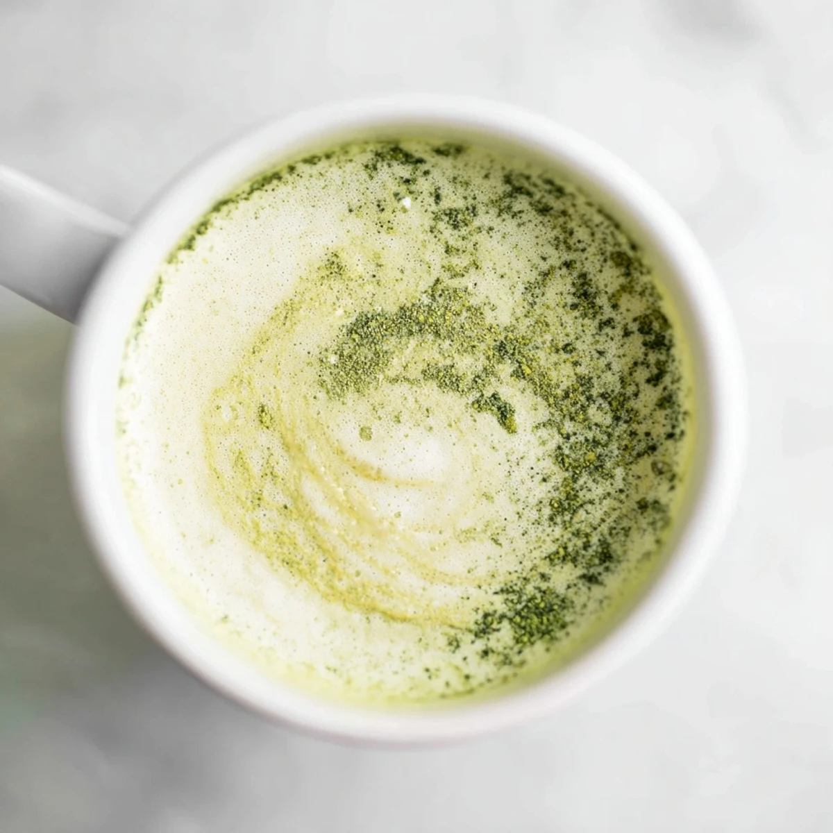 A vibrant Green Matcha Latte with Almond Milk in a clear glass, showcasing its creamy green swirl over ice for a refreshing vegan beverage.