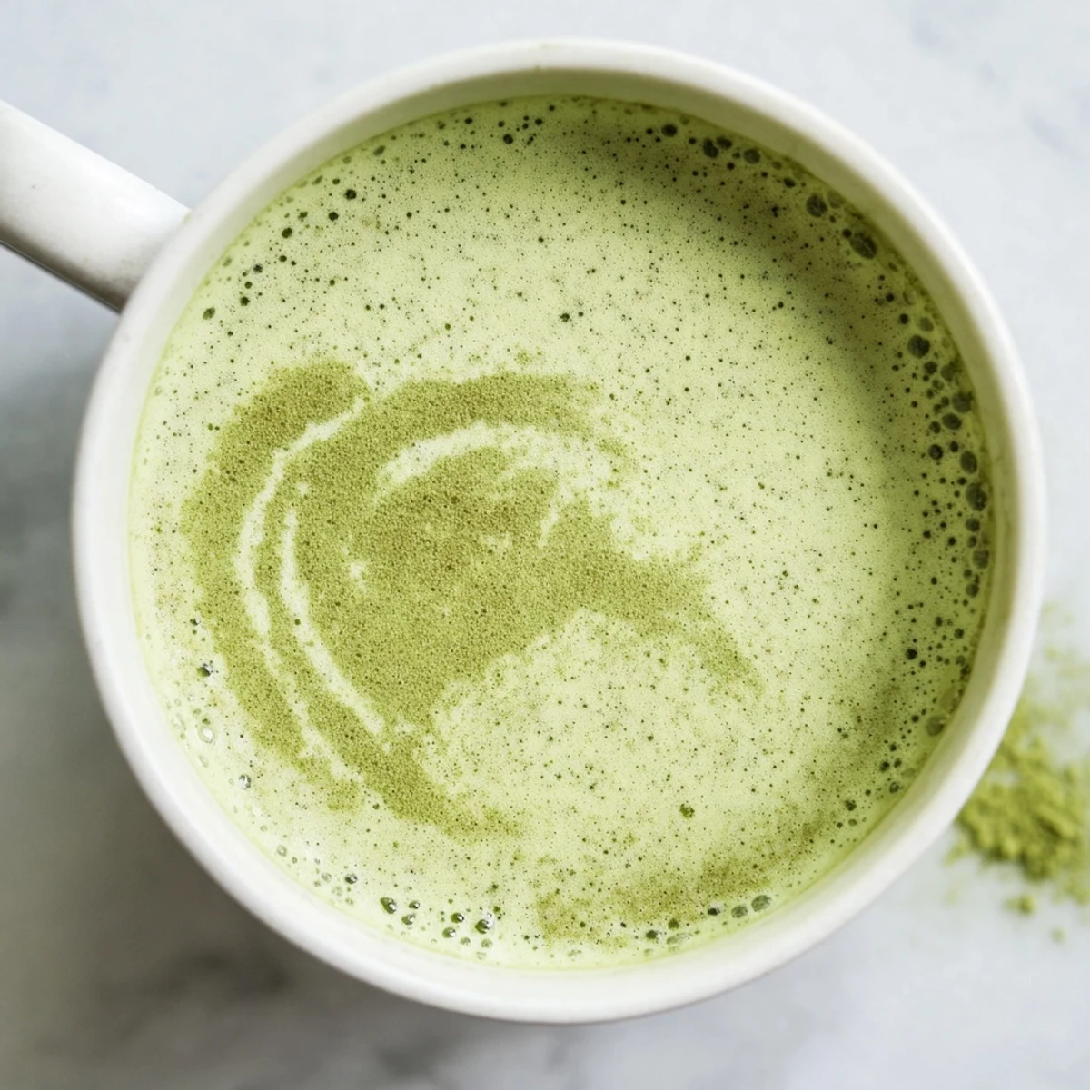 Steaming Green Matcha Latte with Almond Milk served in a cozy mug, garnished with a light dusting of matcha powder for an earthy aroma.