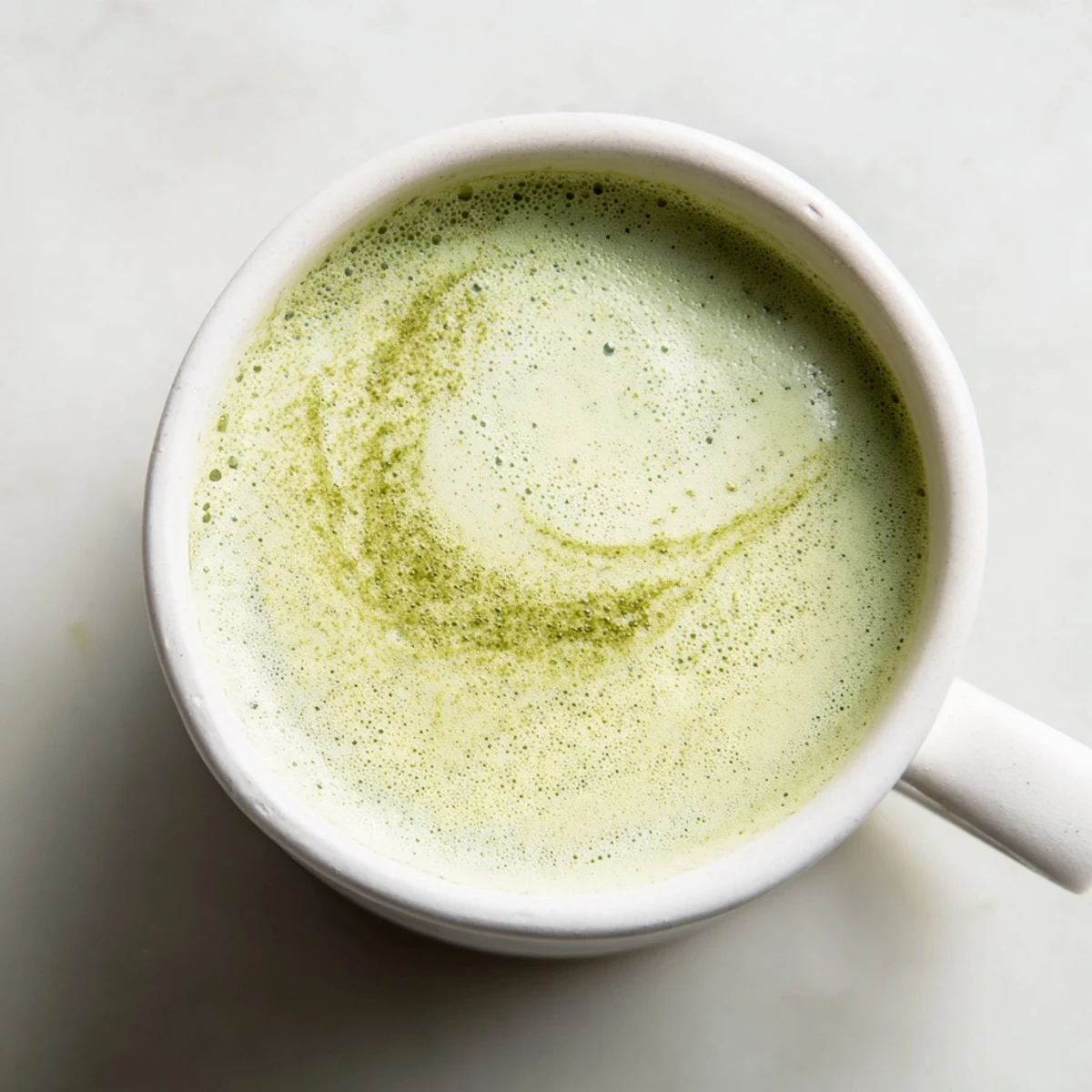 Close-up of a freshly made Green Matcha Latte with Almond Milk, topped with velvety foam, ready to sip for a calming antioxidant boost.
