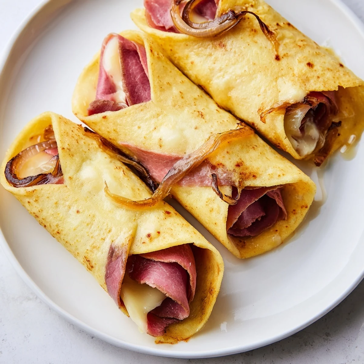 Sliced Easy French Dip Tortilla Roll Ups on a rustic plate, showcasing caramelized onions and melted cheese inside, with a cup of savory beef au jus for dipping.