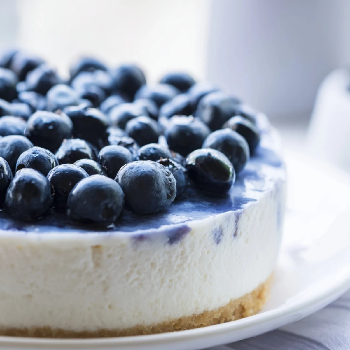 Slice of Blueberry Mousse Cheesecake topped with a vibrant purple blueberry mousse and fresh berries.