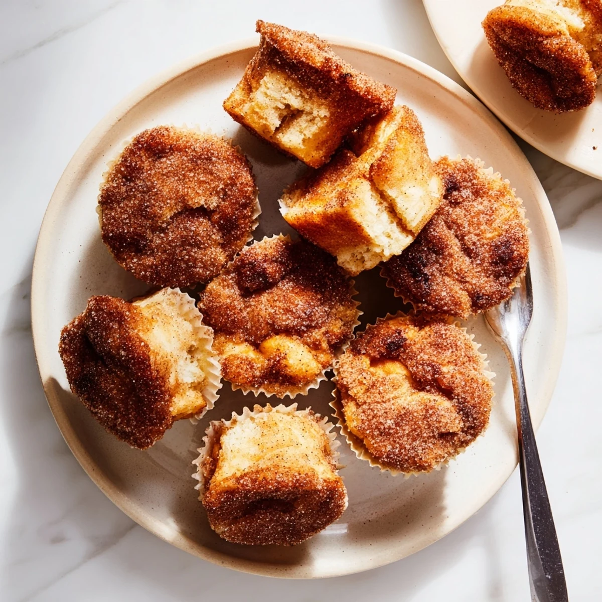 Freshly baked Cinnamon Sugar French Toast Muffins in a tin, glistening with melted butter and a sparkling cinnamon sugar topping.