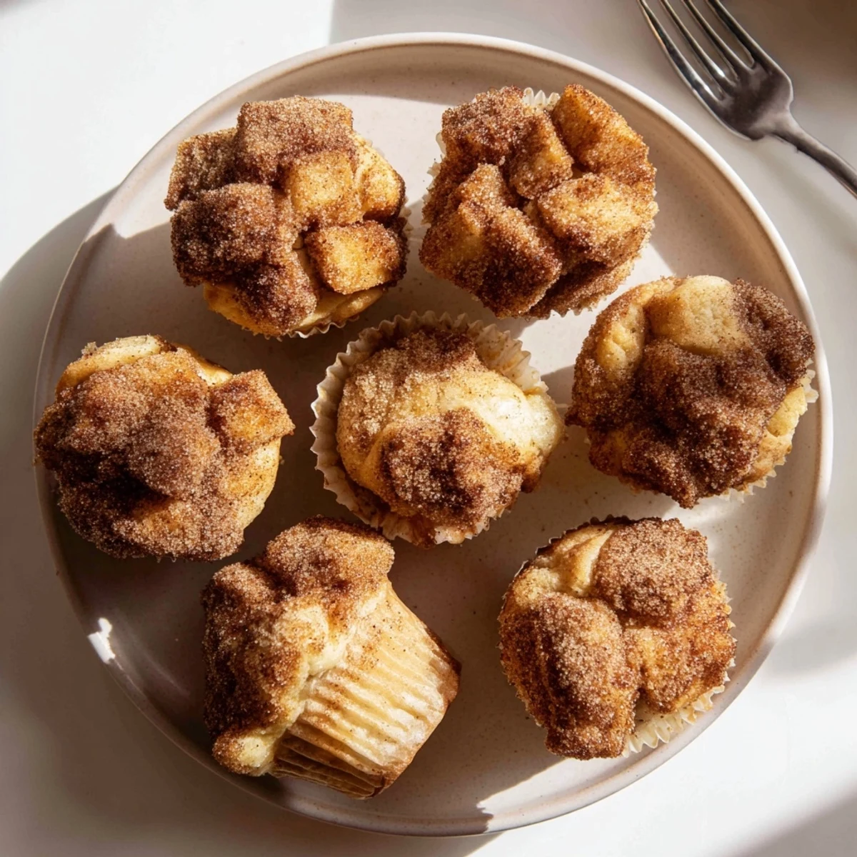 Golden brown Cinnamon Sugar French Toast Muffins sit on a cooling rack, ready to be served with maple syrup and fresh berries.