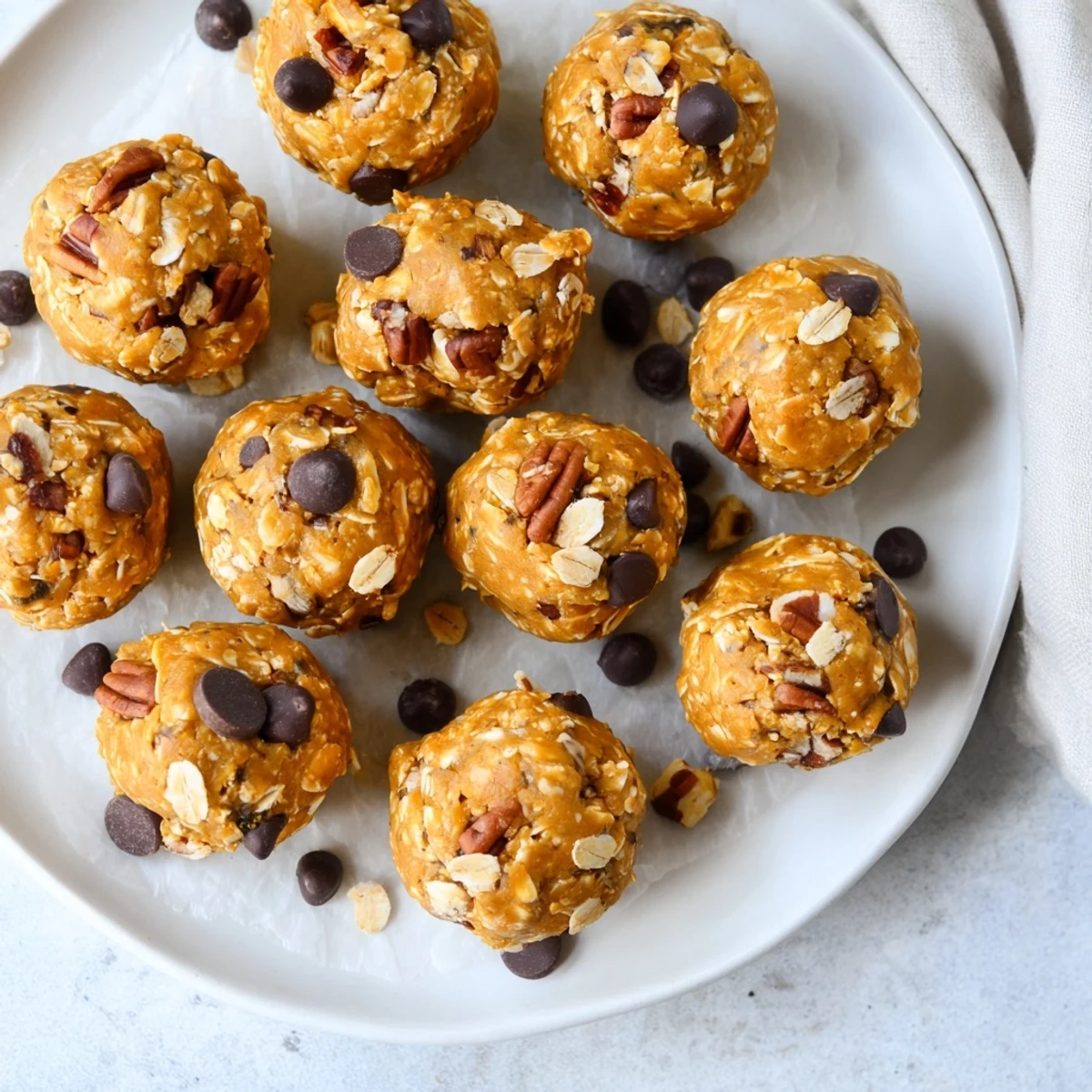 No Bake High Protein Pumpkin Bites with chocolate chips and chopped nuts on a tray.