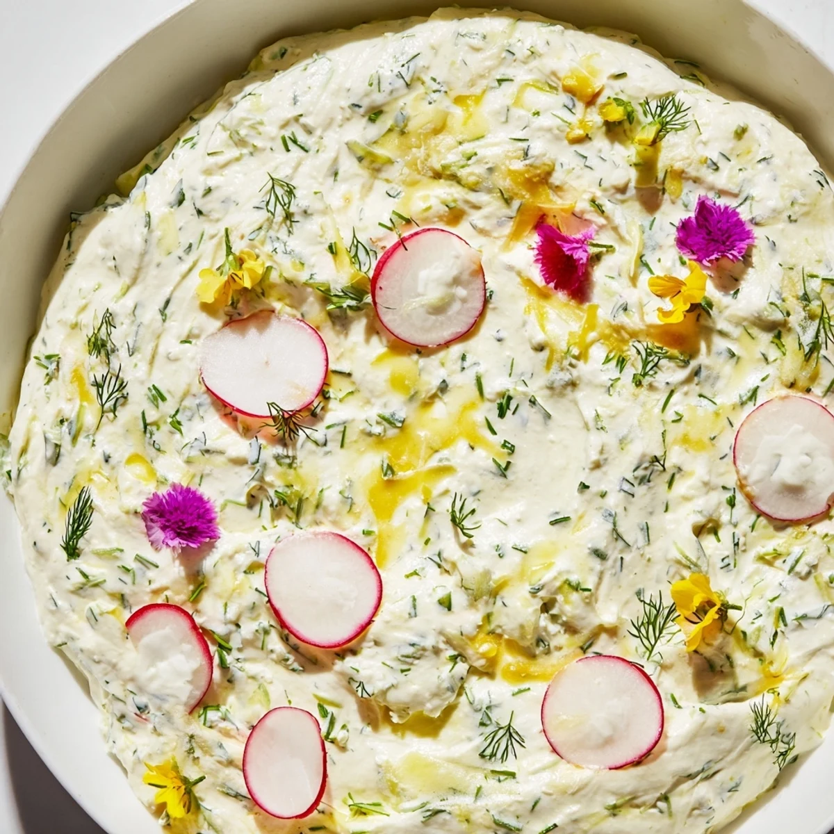 A close-up of creamy Simple Easter Herb Cheese Dip, showing smooth texture and flecks of green herbs, with a rustic wooden serving board nearby.