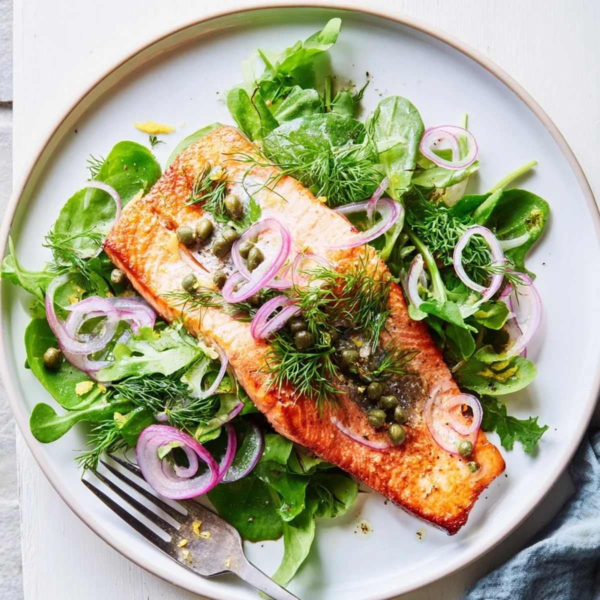 Crispy Skin Tasmanian Atlantic Salmon glistens golden brown on a bed of peppery arugula, garnished with fresh dill and lemon zest.