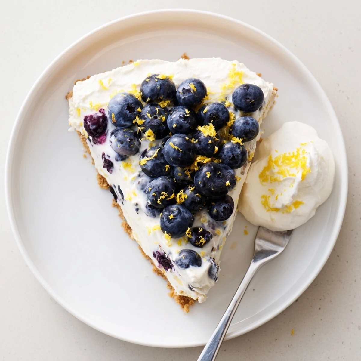 Creamy no bake lemon blueberry cream cake topped with fresh blueberries and lemon zest