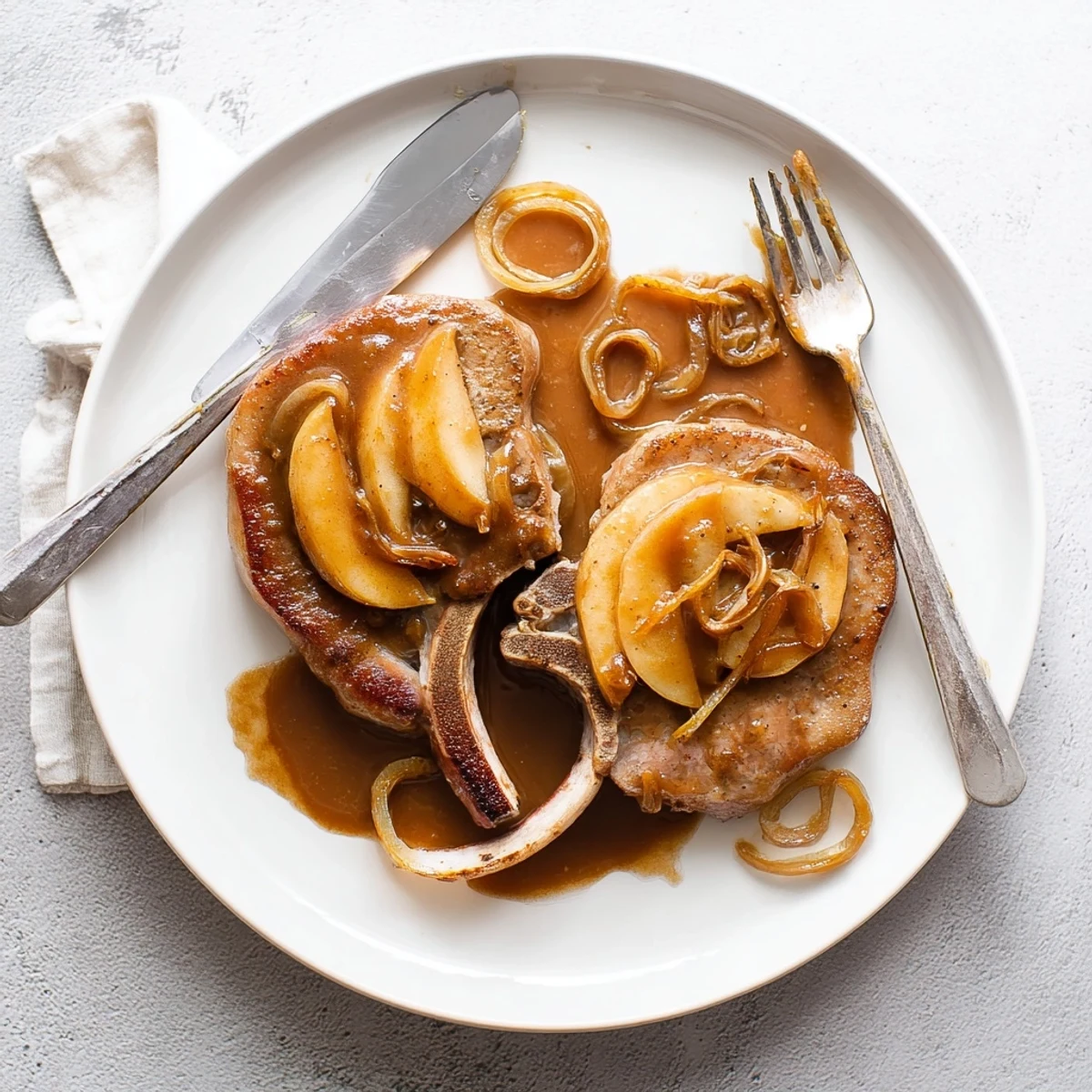 Golden brown pan-seared apple butter pork chops glazed with sweet spiced apple sauce