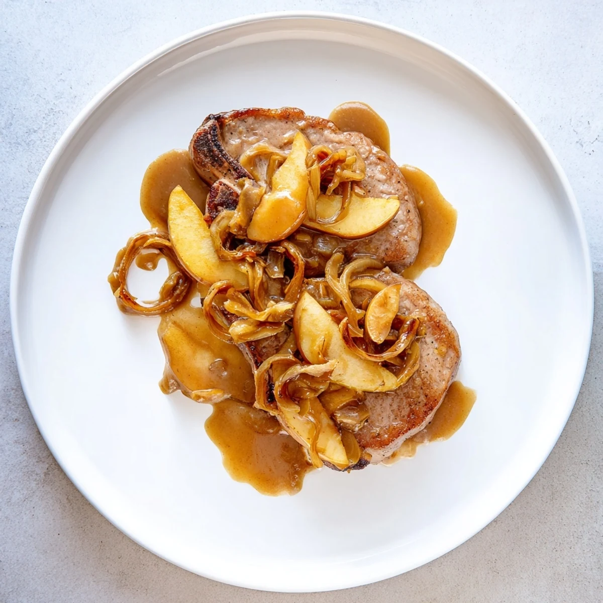 Juicy skillet cooked apple butter pork chops served with cinnamon spiced apple topping