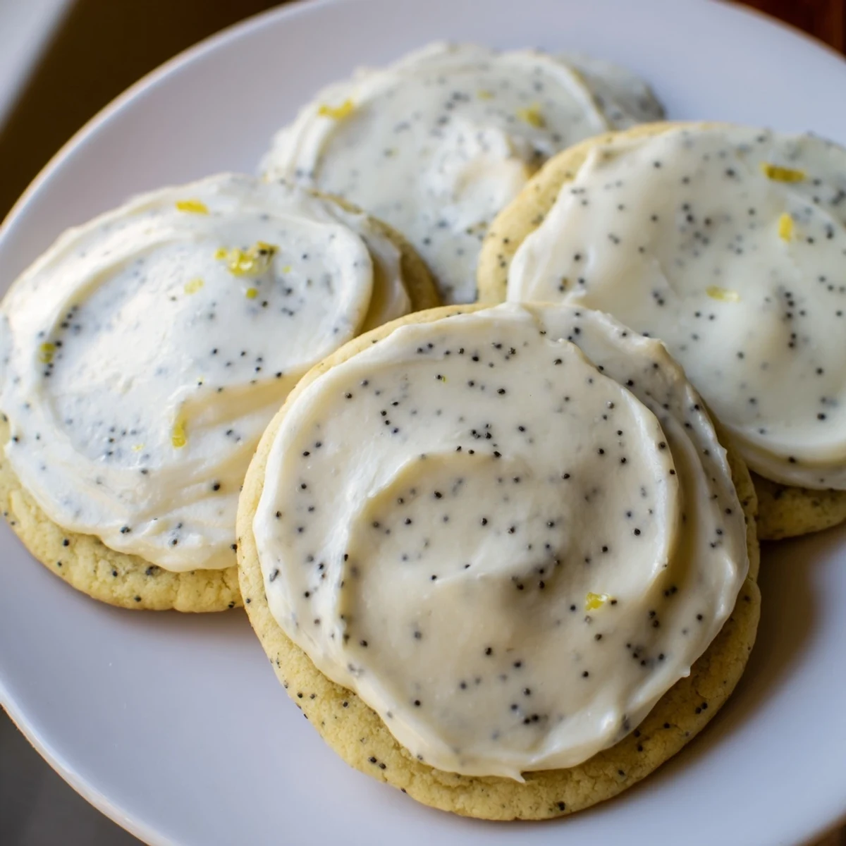 Golden lemon poppy seed cookies with cheesecake frosting piped high atop each buttery cookie
