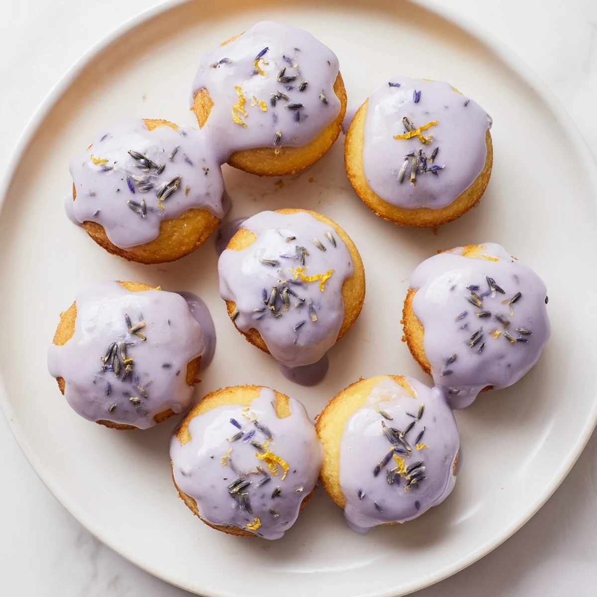 Teatime mini lemon cakes topped with floral lavender icing and garnished with zest