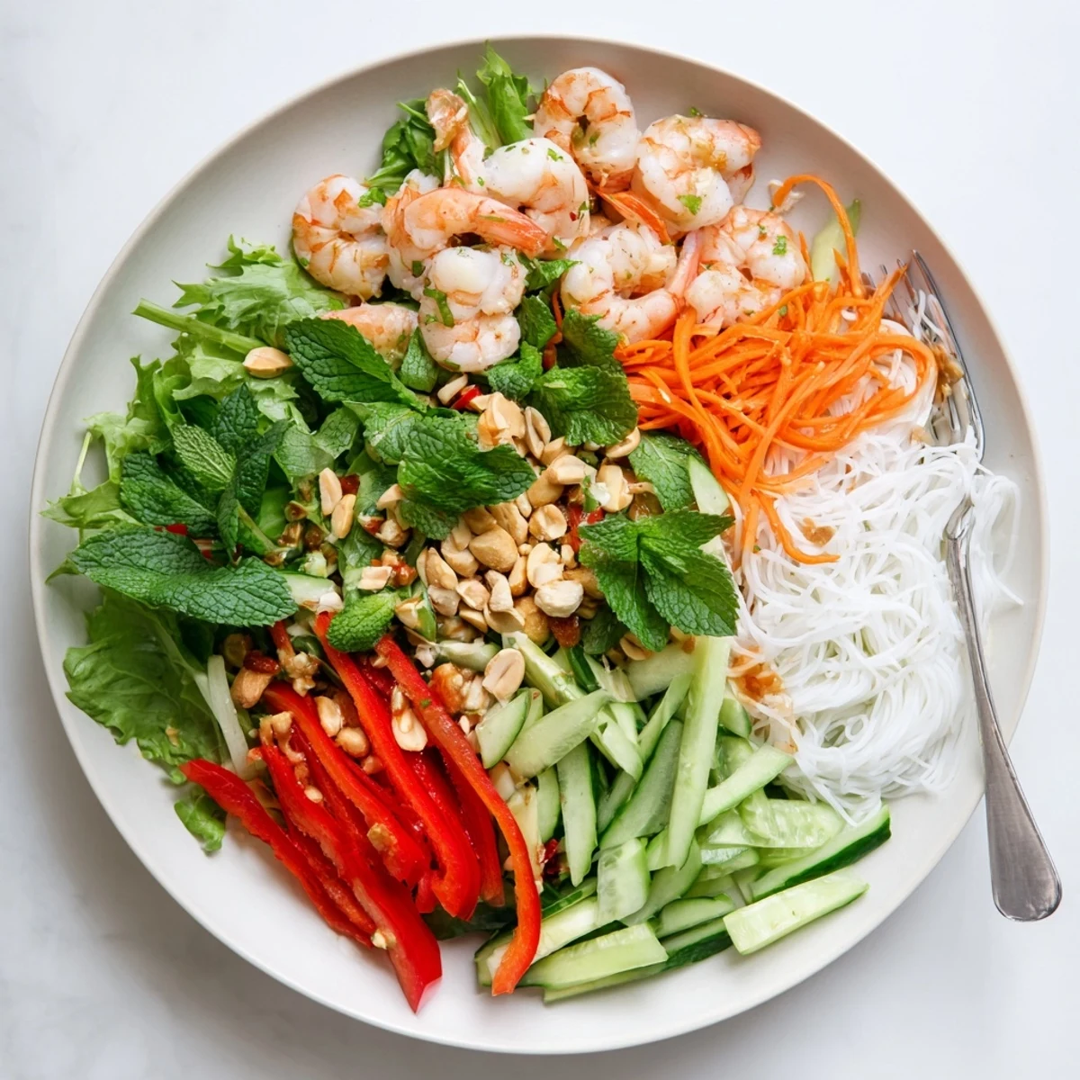 Vibrant bowl of Spring Roll Salad featuring rice noodles, tender shrimp and peanuts coated in spicy ginger dressing