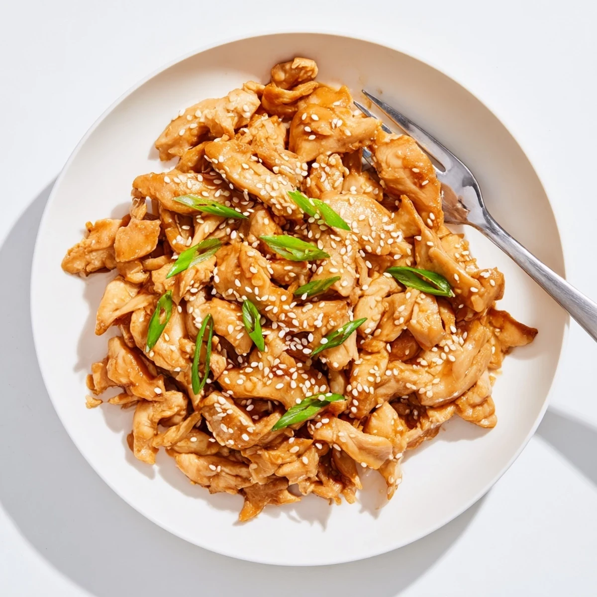 Slow cooker Crock Pot Sesame Chicken with tender pieces coated in glossy caramelized sauce and garnished with white sesame seeds and fresh green onion slices
