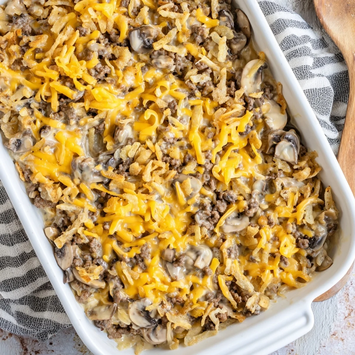 Comforting hamburger mushroom bake dish featuring seasoned beef sliced mushrooms and creamy cheesy sauce in baking pan