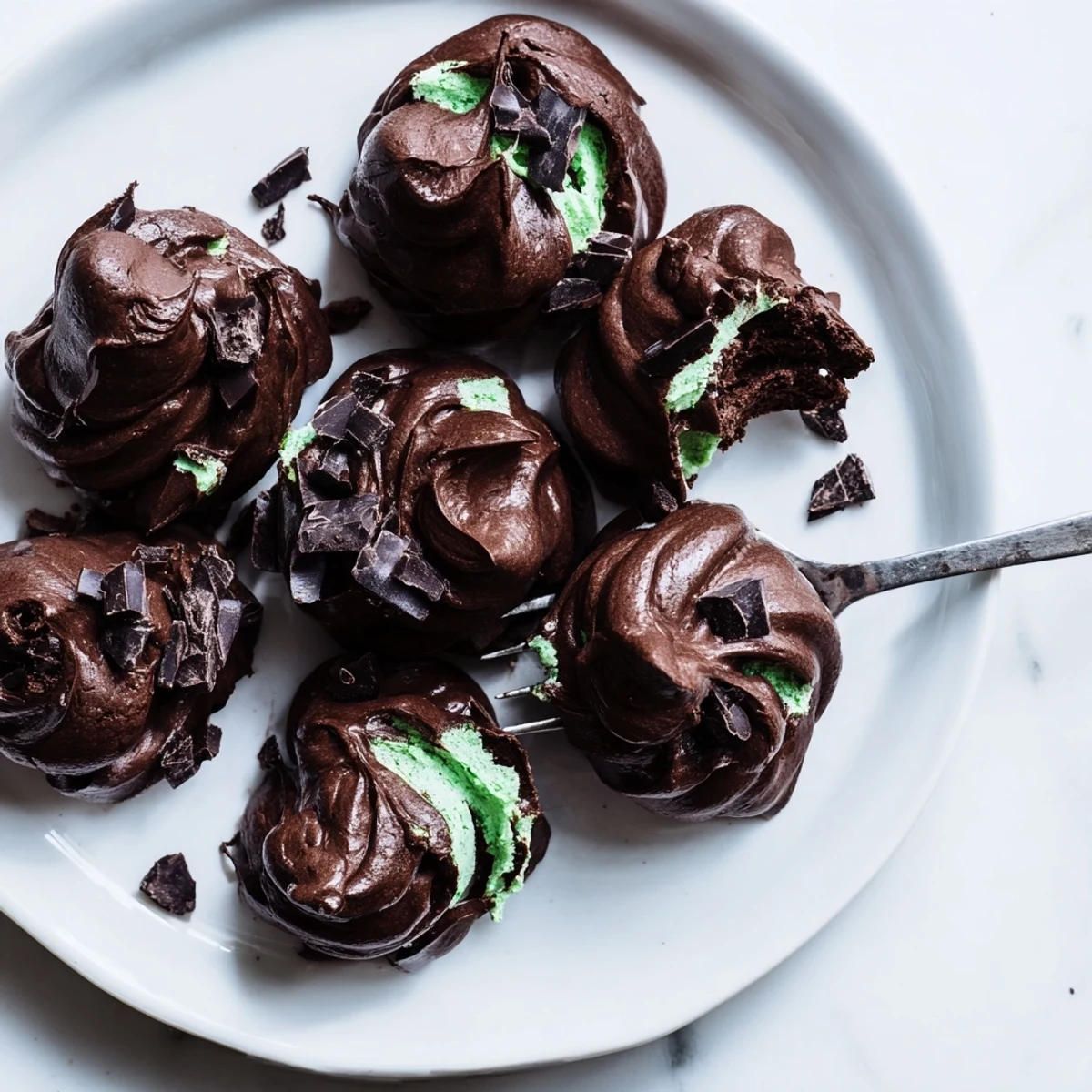 Glossy meringue cookies studded with dark chocolate chunks and mint chips ready for baking
