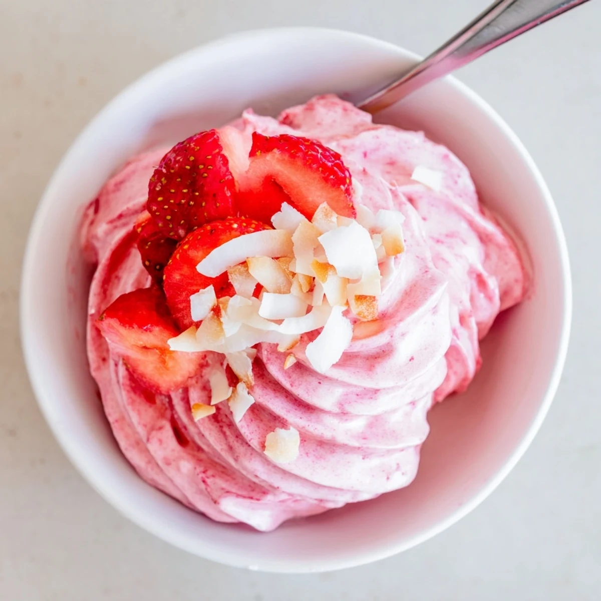 Vegan frozen strawberry Dole Whip soft serve dessert topped with toasted coconut flakes