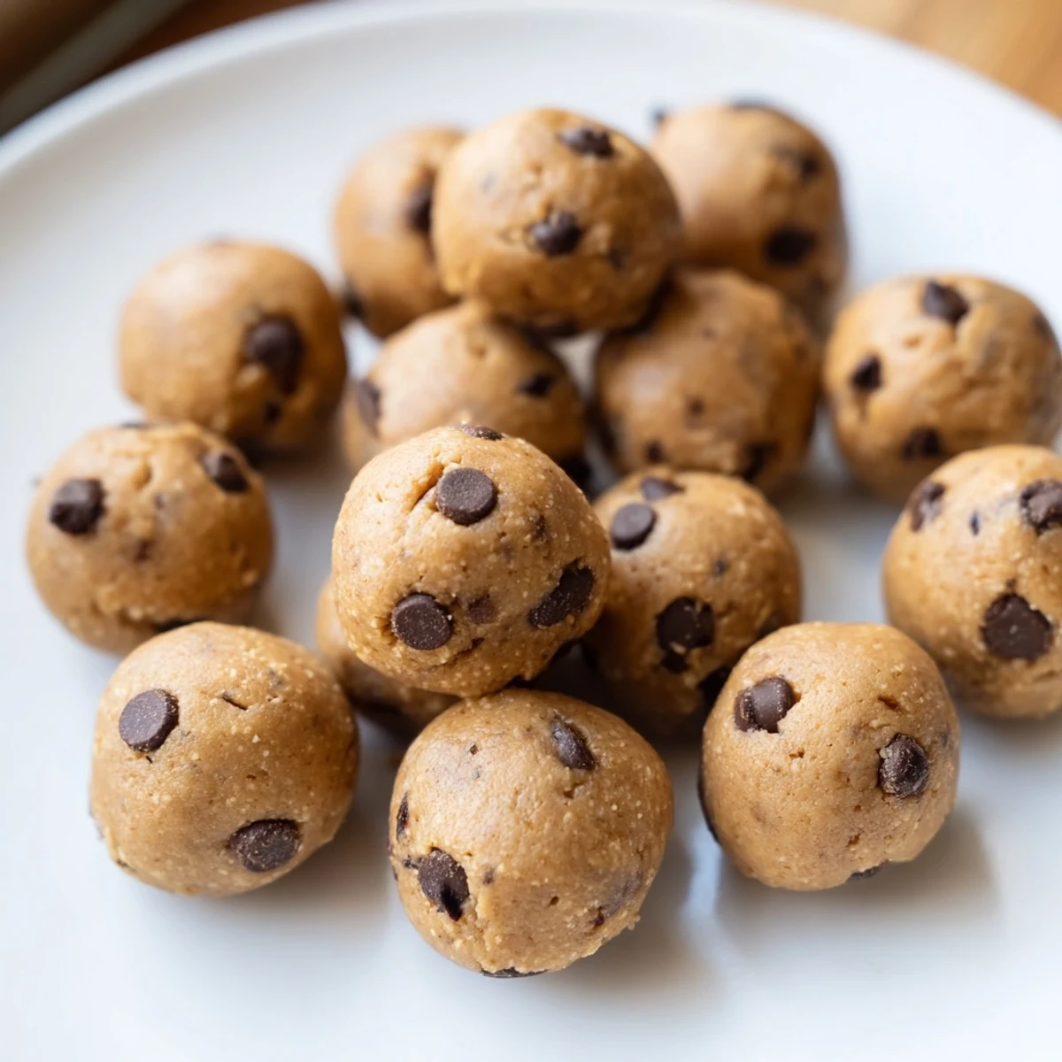 No-bake chocolate chip cookie dough protein balls arranged on a wooden board ready for healthy snacking