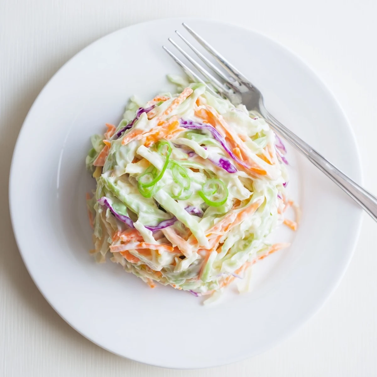 Bowl of refreshing easy creamy coleslaw featuring finely shredded vegetables in smooth white dressing