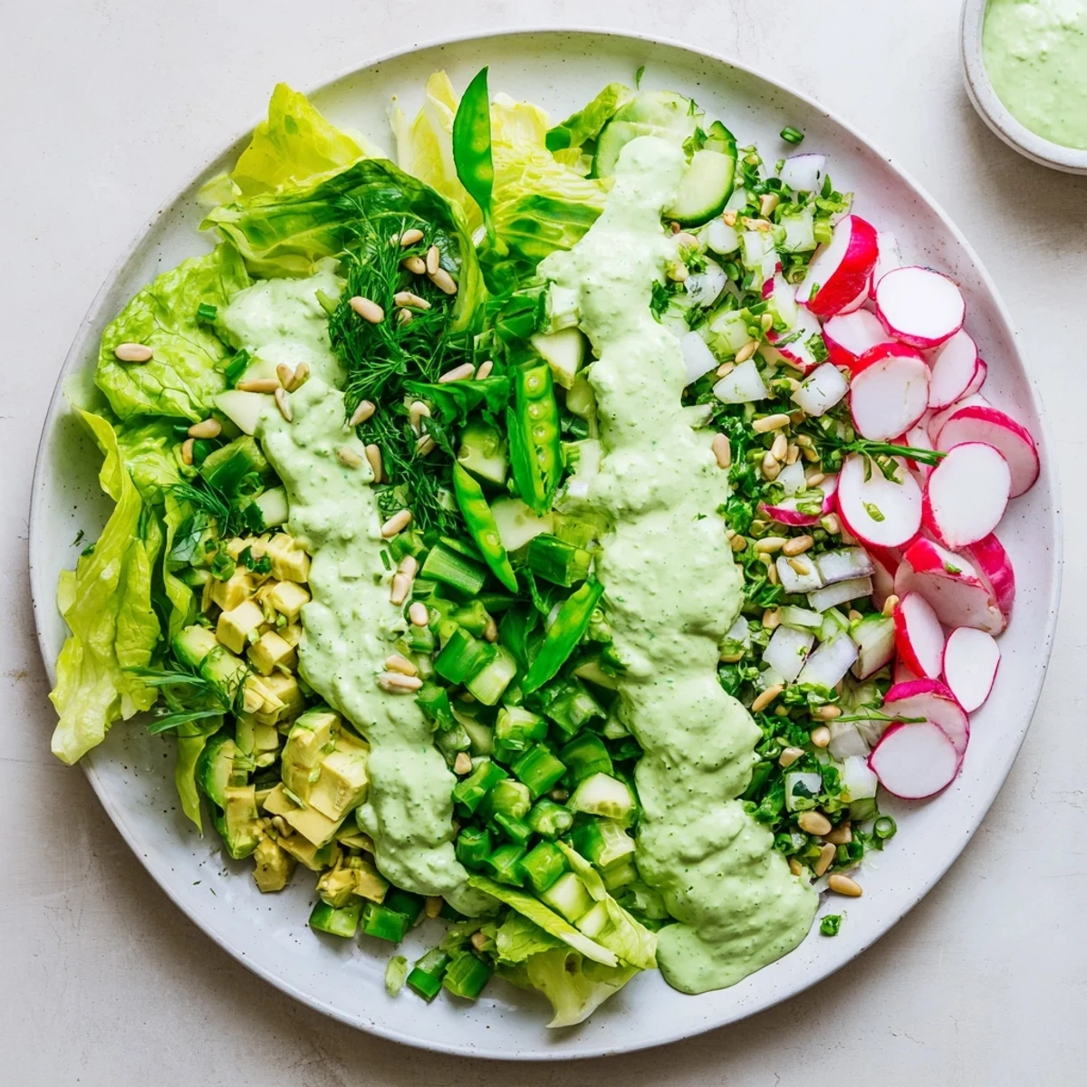 Colorful Fresh Green Goddess Salad bowl with crisp vegetables, creamy avocado, and vibrant herb dressing drizzled over crisp greens