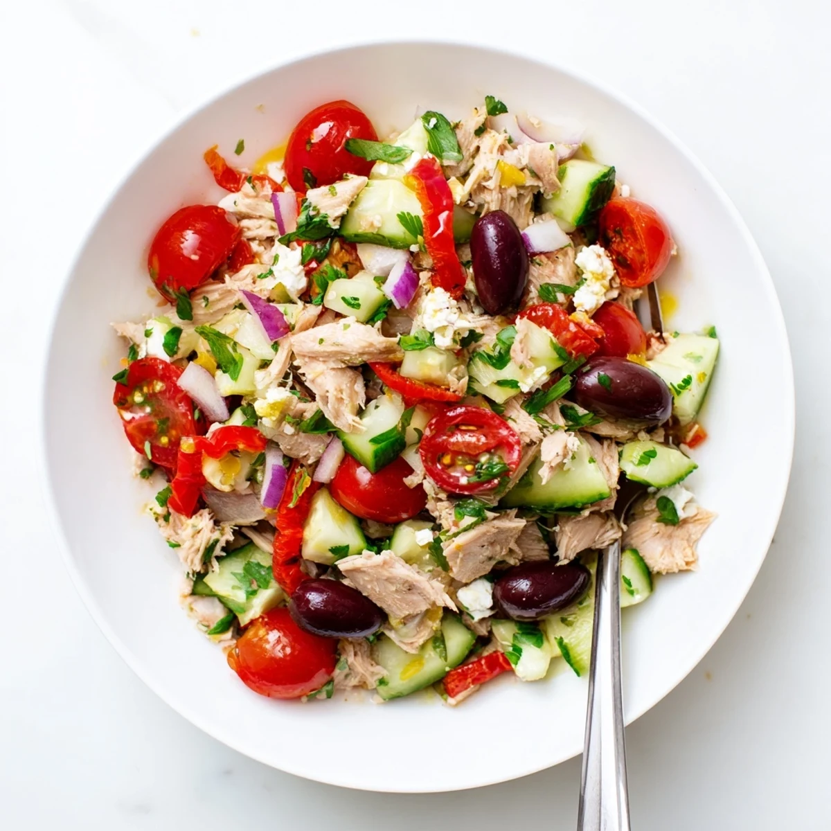 Colorful Mediterranean tuna salad bowl with fresh vegetables, olives, and lemon drizzle