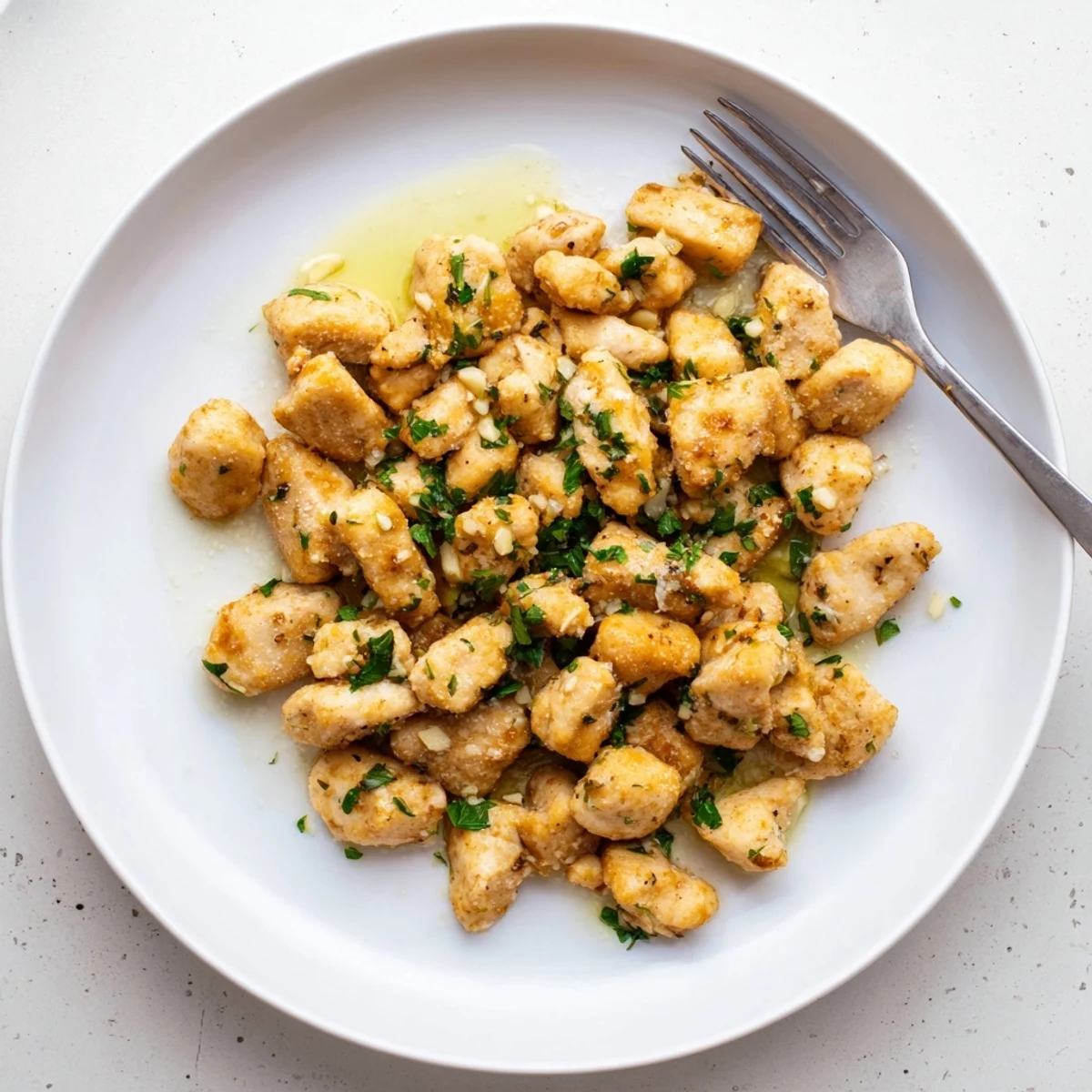 Tender seared chicken pieces coated in creamy garlic butter sauce served with lemon wedges