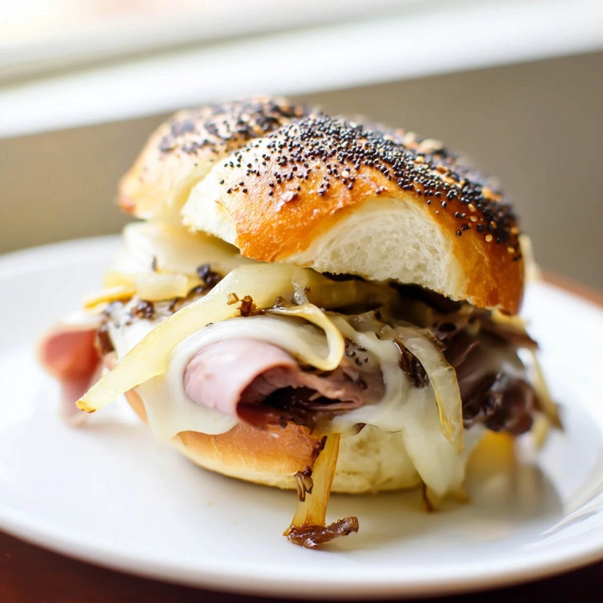 Mini French dip sliders with tender beef, melted cheese, and sweet onions ready for parties