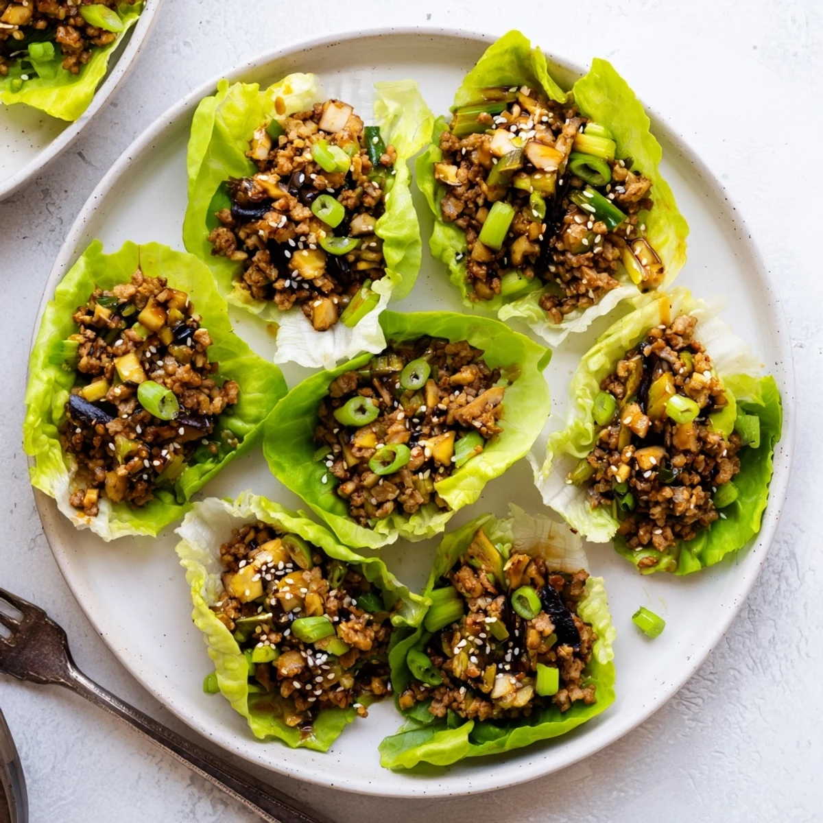 Golden brown ground chicken filling spooned into crisp butter lettuce cups for Easy Chicken Lettuce Wraps