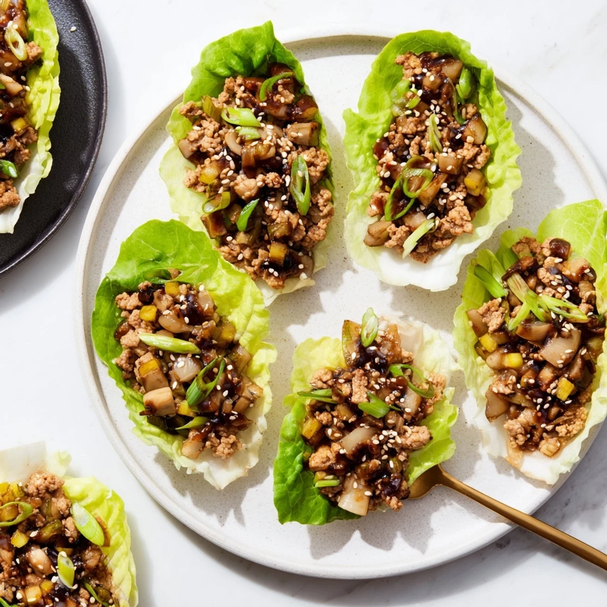 Fresh Easy Chicken Lettuce Wraps garnished with sesame seeds and sliced green onions on a white serving platter
