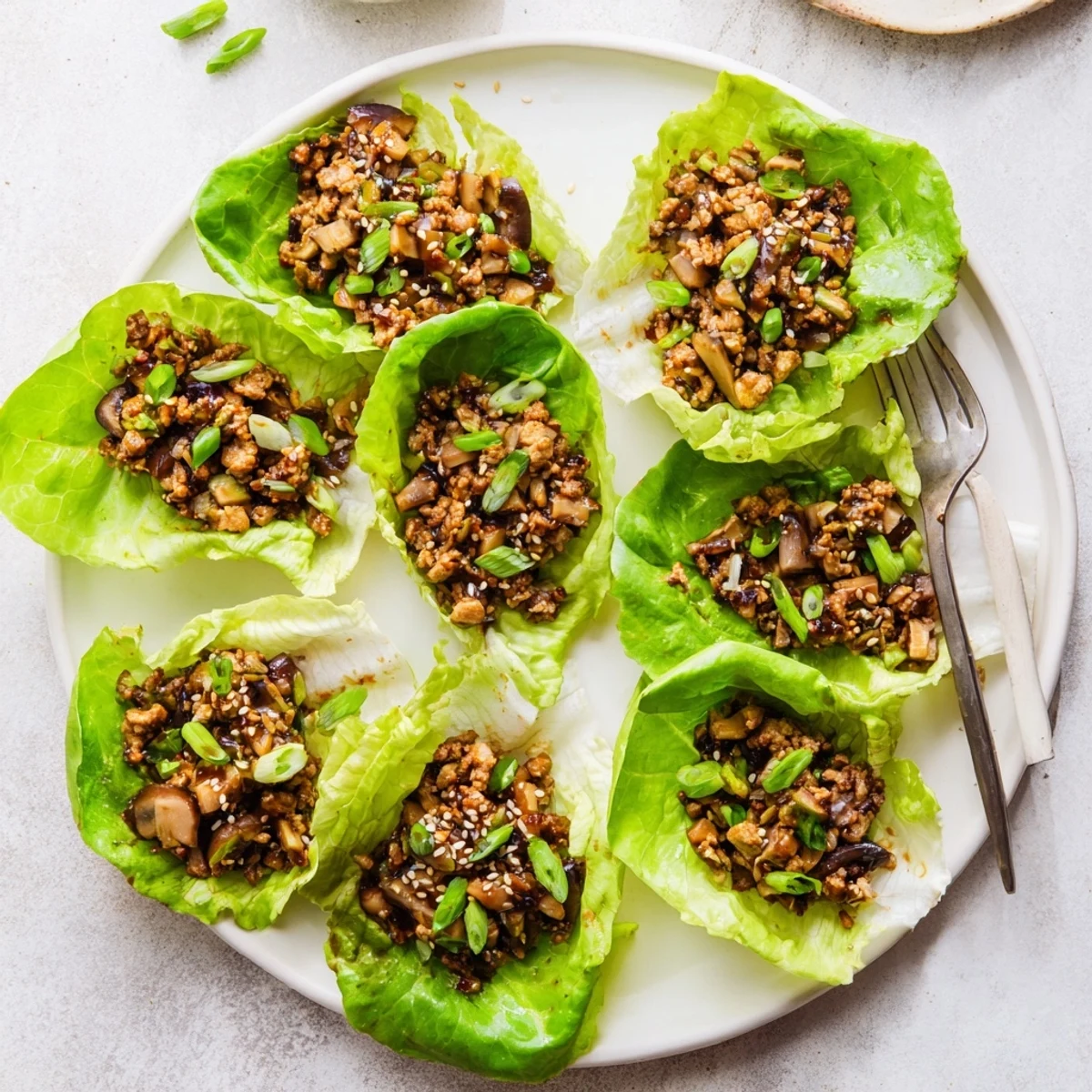 Savory Easy Chicken Lettuce Wraps featuring glossy glazed chicken mixture with water chestnuts in green lettuce leaves
