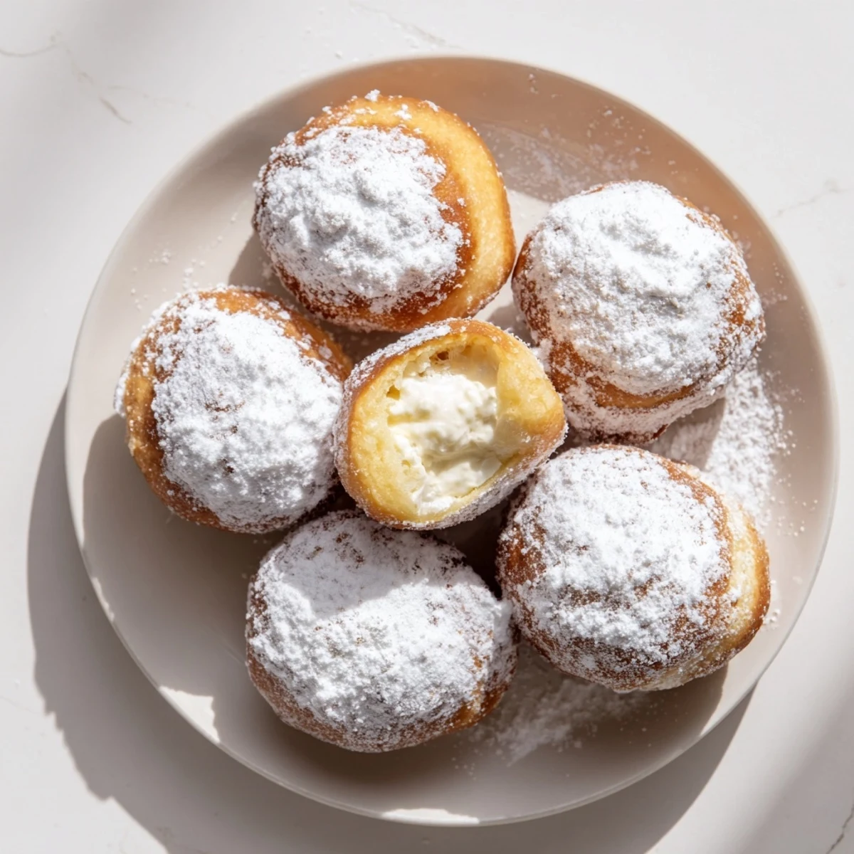 Golden brown Korean milk cream donuts dusted with powdered sugar on a white plate