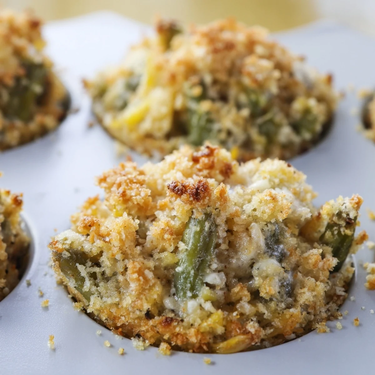 Individual muffin-sized green bean casserole portions featuring creamy Parmesan sauce and tender crisp beans