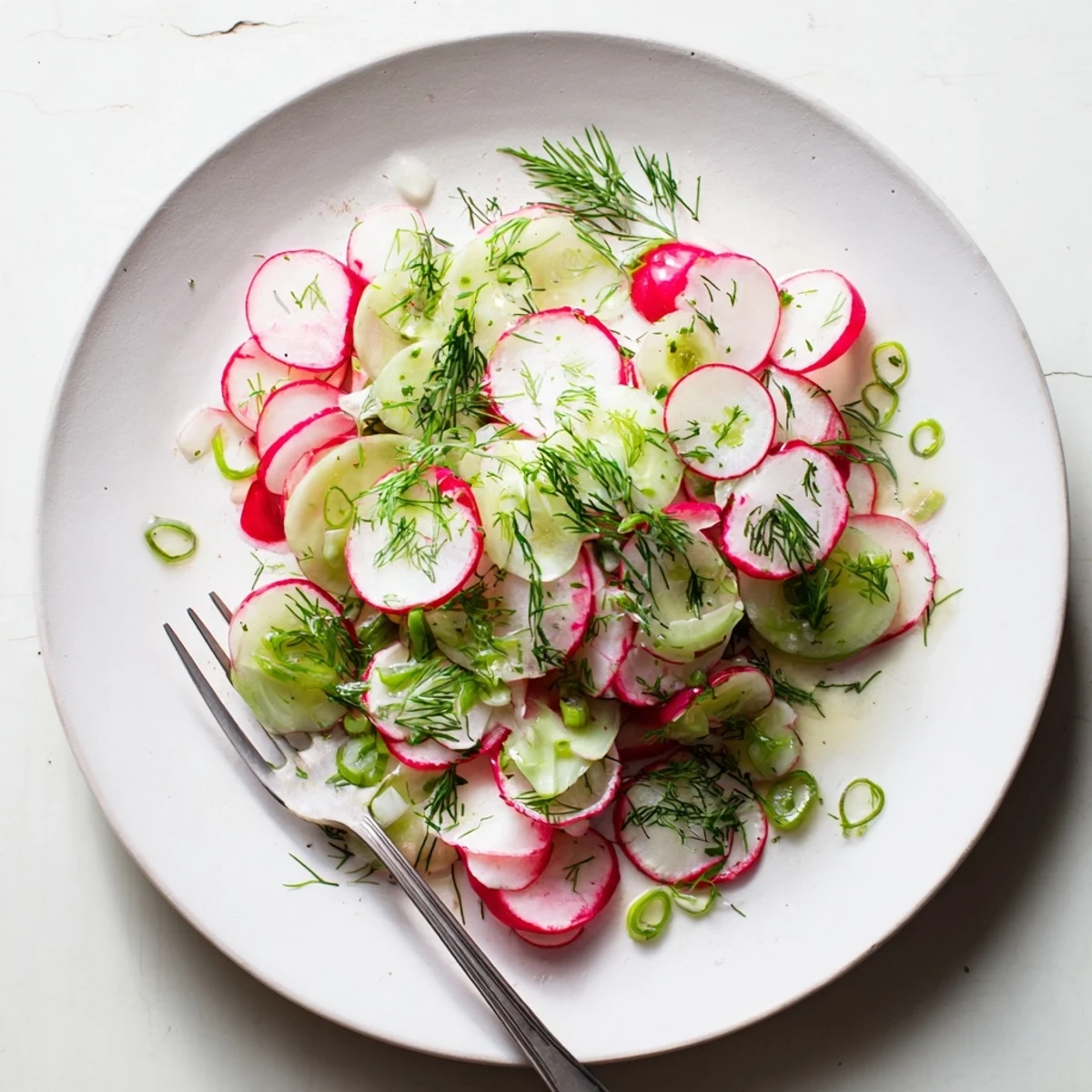 Colorful radish and cucumber salad with green onions and fresh herbs drizzled with olive oil dressing