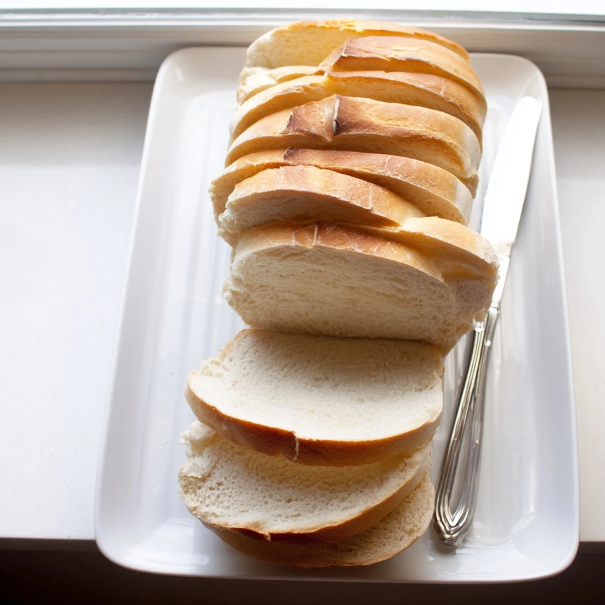Two fluffy loaves of freshly baked Amish white bread cooling on wire rack